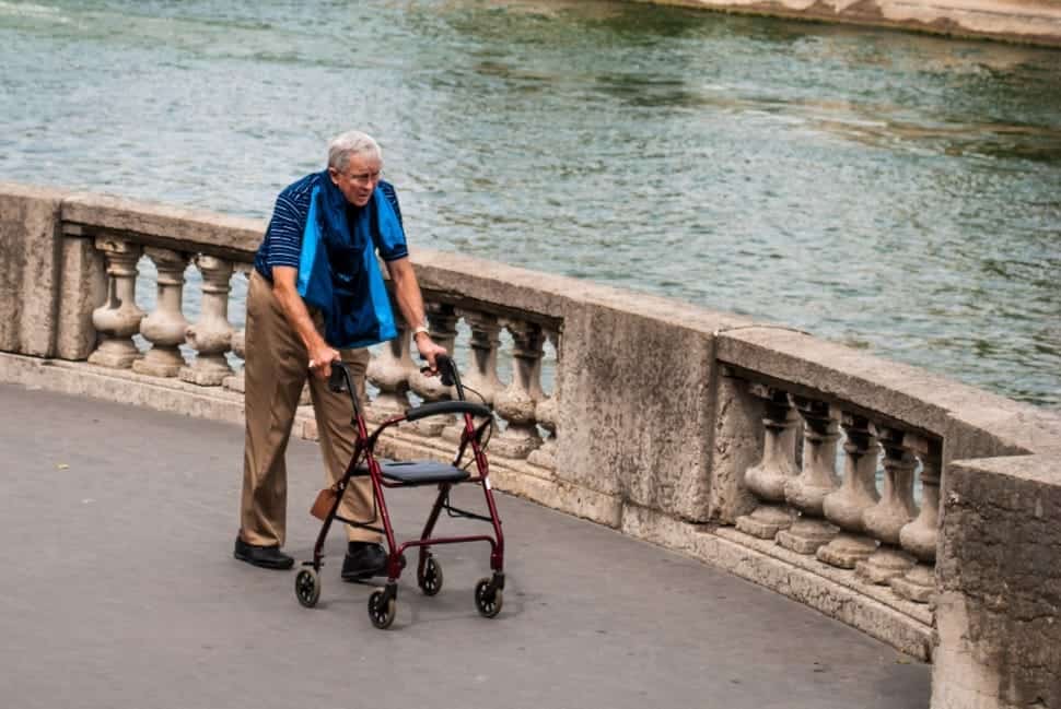 old big and tall man using a walker by the water